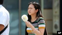 گرمای شدید هوا و یک زن ژاپنی که یک پنکه کوچک همراه خود دارد - ۲۳ ژوئیه ۲۰۱۸
