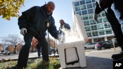Pest Control Officer Gregory Cornes uses a trowel to scoop up dry ice before dropping it directly into rat burrows, as his co-worker Curtis Redman assists, near the Capitol in Washington, Nov. 21, 2018.