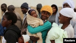 Zimbabwean women react as they wait to casts their votes at a polling station in Domboshava, about 45 km (28 miles) north of Harare July 31, 2013. Zimbabweans voted in large numbers on Wednesday in a fiercely contested election pitting veteran President R