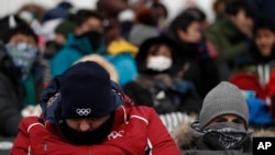 Spectators, with their faces covered, waiting for the start of the women's slopestyle qualifications at Phoenix Snow Park at the 2018 Winter Olympics in Pyeongchang, South Korea, Feb. 11, 2018.