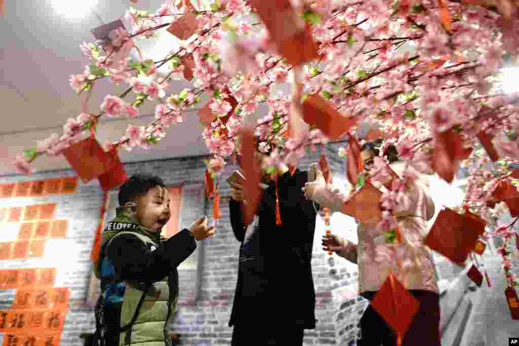 2018年2月10日，中国上海举办的农历新年庆祝活动中，一位男孩在祈祷树下玩耍。世界各地的华人正准备在2月16日庆祝农历新年，家人聚会，放鞭炮，吃传统美食，欢迎狗年。