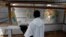 FILE - A priest watches as health workers dressed in Ebola protective suits prepare the body of an Ebola patient for burial at the Ebola treatment center in Butembo, in the Democratic Republic of Congo, March 26, 2019. 