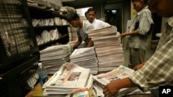 Seorang pekerja di sebuah kantor distribusi koran dan majalah di New Delhi, India (tengah belakang) tengah melayani seorang pelanggan (Foto: dok).