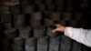 FILE - A man stacks coal briquettes at his courtyard in Beijing, Nov. 18, 2014. Many people living in old houses still rely on coal for heat in winter.