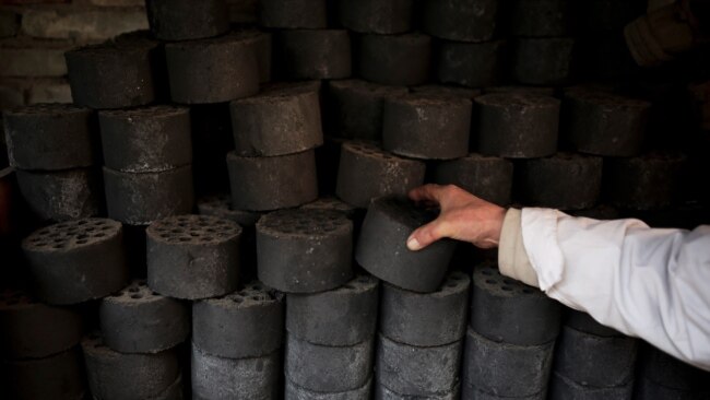 A man stocks up coal briquettes at his court yard, as many people living in old houses still rely on coal fire to heat up in the winter season, in Beijing, China, Nov. 18, 2014.
