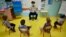 FILE - In this file photo taken on May 12, 2020, a teacher wearing a protective mask teaches children in her classroom at Champ l'Eveque public school in Bruz, western France. 