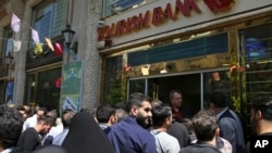 Iranians stand in front of a bank, hoping to buy U.S. dollars at the new official exchange rate announced by the government, in downtown Tehran, April 10, 2018. Iran moved this week to enforce a single exchange rate to the dollar, banning all unregulated trading.