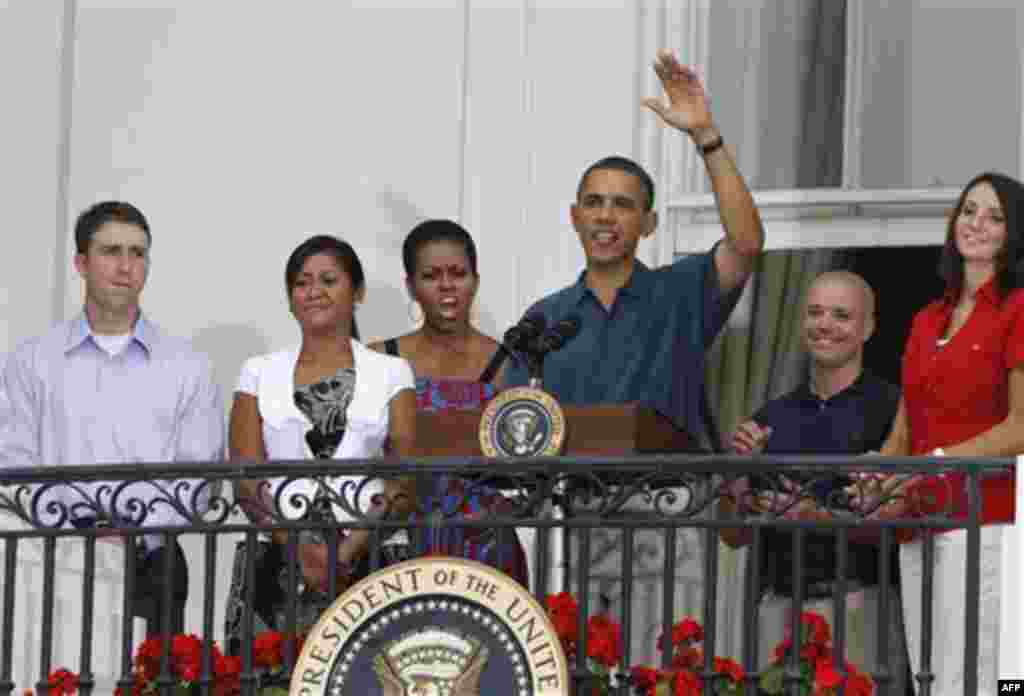 President Barack Obama and first lady Michelle Obama stand with unidentified service members as they welcome military families to an Independence Day celebration on the South Lawn of the White House in Washington, Monday, July 4, 2011. (AP Photo/Charles D