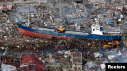 Warga setempat mengamati kapal yang terhempas topan Haiyan di tengah kota Tacloban Filipina tengah (21/11).