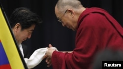 The Dalai Lama gives a Tibetan shawl to Japan's main opposition Liberal Democratic Party president Shinzo Abe, at the upper house members' office building in Tokyo, November 13, 2012.