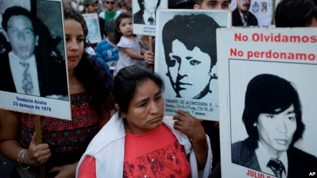 La gente lleva fotos de las víctimas de la dictadura de 1976-83, durante una marcha que conmemora el 41 aniversario del golpe militar en Buenos Aires, Argentina, el viernes 24 de marzo de 2017.