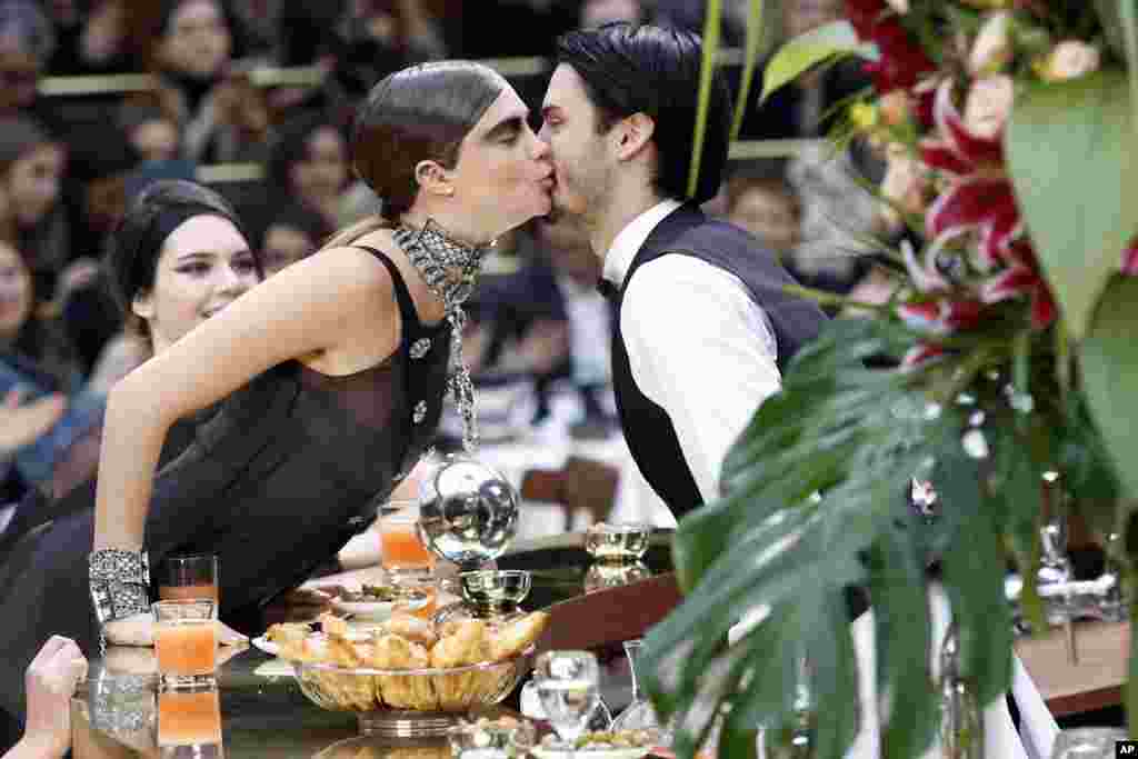 Model Cara Delevingne, kissing a waiter, wears creations of Chanel&#39;s ready to wear fall-winter 2015-2016 fashion collection during Paris fashion week in France.