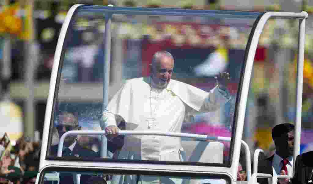 Pope Francis waves to people waiting to welcome him on the outskirts of Colombo, Sri Lanka, Jan. 13, 2015.