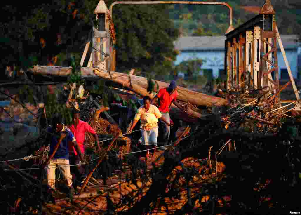 Survivors of Cyclone Idai cross a temporary bridge as they arrive at Coppa business center to receive aid, in Chipinge, Zimbabwe.