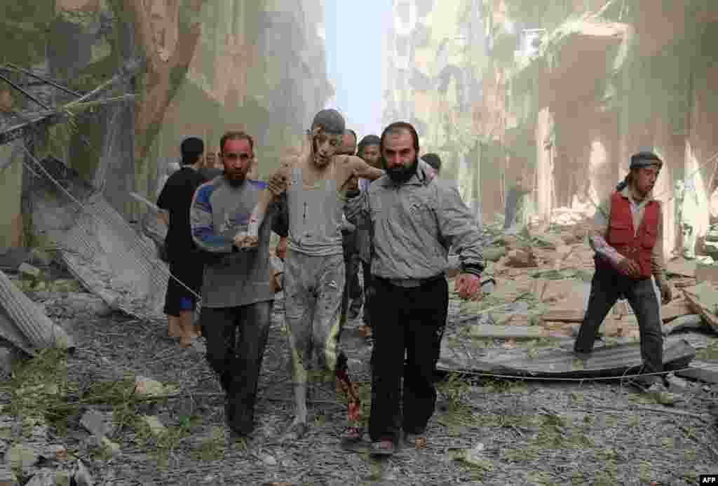 Syrians help a wounded youth following an air strike on the Fardous rebel held neighborhood of the northern Syrian city of Aleppo.