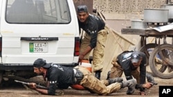 Pakistani police commandos take position outside one of the two stormed mosques by gunmen in Lahore, 28 May 2010