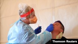 A health care worker tests a patient for COVID-19 at a testing facility in Kilmore outside of Melbourne, Australia, Oct. 6, 2020.