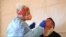 A health care worker tests a patient for COVID-19 at a testing facility in Kilmore outside of Melbourne, Australia, Oct. 6, 2020.