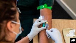 A paramedic, left, takes a blood sample from a medical worker, during an antibody testing program at the Hollymore Ambulance Hub, in Birmingham, England, on Friday, June 5, 2020. Making antibody tests widely available may help Britain lift its…