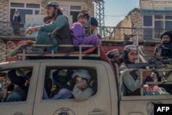 Taliban members drive along a road in the center of Kabul, Oct. 14, 2021.