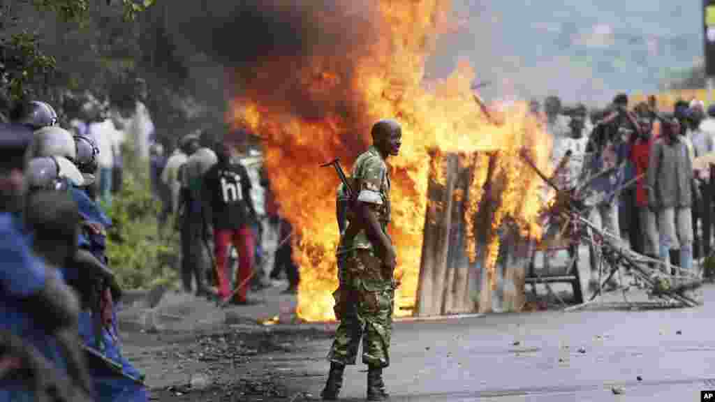 Mwanajeshi asimama kati ya waandamanaji wanaotia moto uchafu barabarani na polisi wa kupambana na ghasia huko kata ya Musaga mjini Bujumbura, May 4, 2015.