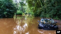 FILE - A partially submerged vehicle sits in floodwater from after Hurricane Helene passed the area, in Atlanta, Sept. 27, 2024.