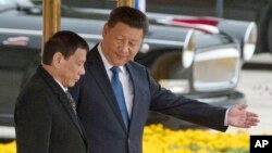 FILE - Chinese President Xi Jinping, right, shows the way to Philippine President Rodrigo Duterte during a welcome ceremony outside the Great Hall of the People in Beijing, China, Thursday, Oct. 20, 2016. (AP Photo/Ng Han Guan)