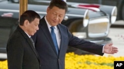 FILE - Chinese President Xi Jinping, right, shows the way to Philippine President Rodrigo Duterte during a welcome ceremony outside the Great Hall of the People in Beijing, China, Oct. 20, 2016.