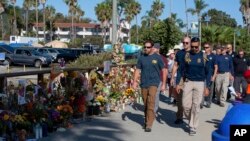 FBI agents walk past a memorial for the victims of the Conception dive boat on the Santa Barbara Harbor, as authorities issue a search warrant for the Truth Aquatics' offices in Santa Barbara, Calif., Sept. 8, 2019. 