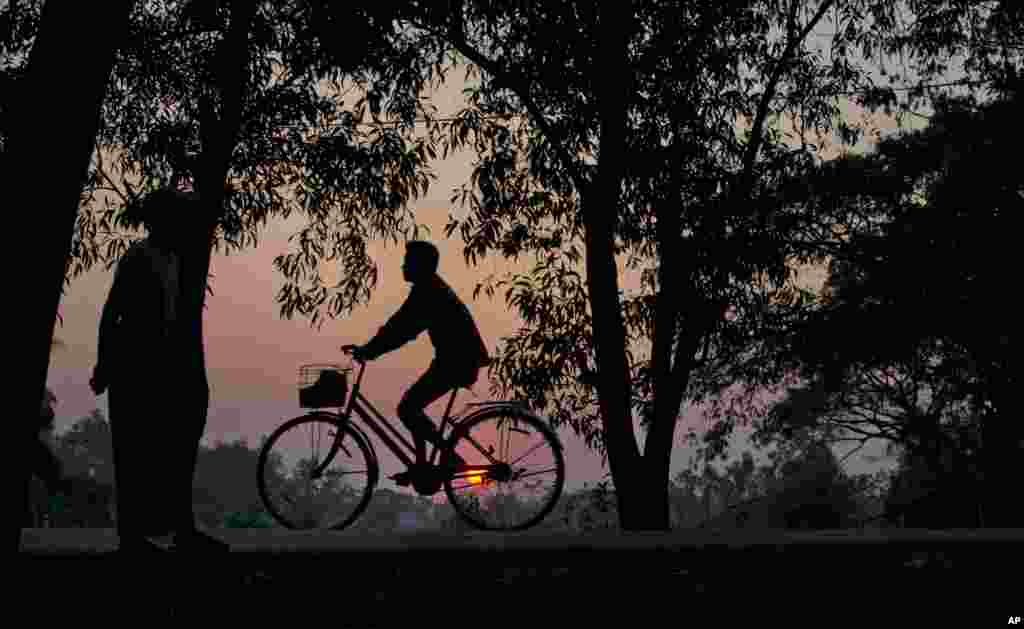 A man rides his bicycle as the sun sets in a suburb of Rangoon, Burma.