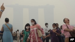Turis di Singapura memakai masker karena asap yang memenuhi udara, saat krisis polusi memuncak Juni 2013.