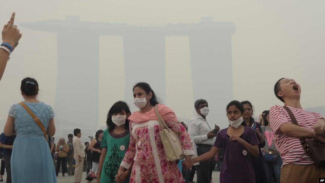 Turis di Singapura memakai masker karena asap yang memenuhi udara, saat krisis polusi memuncak Juni 2013.