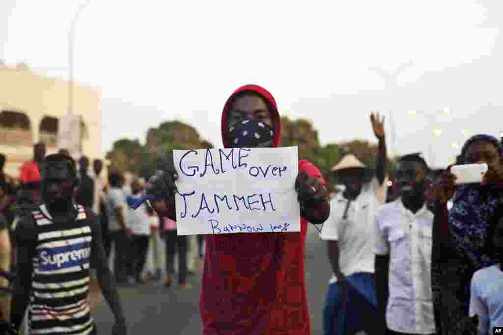 Un homme brandit une affiche avec inscription : "C’est fini pour Yahya Jammeh !" au milieu des manifestants en liesse à Serrekunda, Gambie, 19 janvier 2017.
