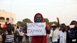 Un homme brandit une affiche avec inscription : "C’est fini pour Yahya Jammeh !" au milieu des manifestants en liesse à Serrekunda, Gambie, 19 janvier 2017.