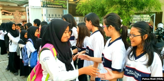 Siswa-siswi SD Kristen Petra Jombang menyalami siswa-siswi Madrasah Ibtidaiyah (MI) Islamiyyah-Plosogenuk yang mengunjungi sekolah mereka (Foto:VOA/Petrus Riski).