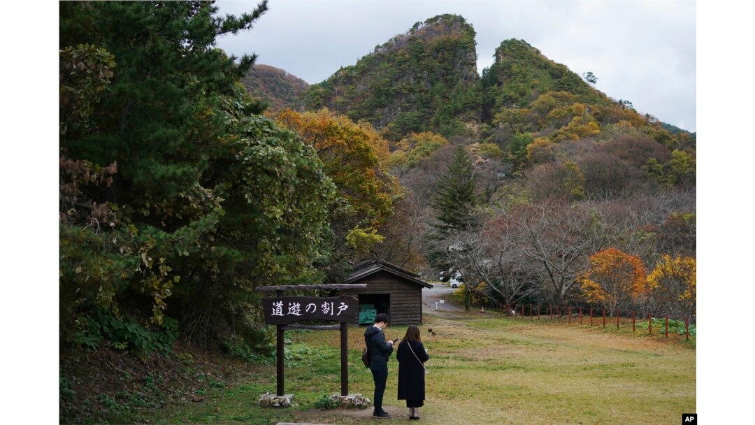 Pengunjung berdiri di dekat Doyu no Warito, sisa simbolis Tambang Emas Sado, di Sado, Prefektur Niigata, Jepang, Minggu, 24 November 2024. (Foto: AP)