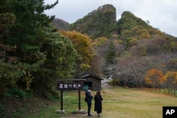 Pengunjung berdiri di dekat Doyu no Warito, sisa simbolis Tambang Emas Sado, di Sado, Prefektur Niigata, Jepang, Minggu, 24 November 2024. (Foto: AP)