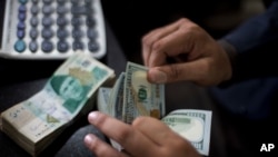 FILE - A money changer counts U.S. dollar bills in Islamabad, Pakistan, Nov. 30, 2018.