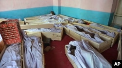FILE - Bodies of civilians and security forces are placed at a hospital in Ghazni province, Afghanistan, Aug. 12, 2018.