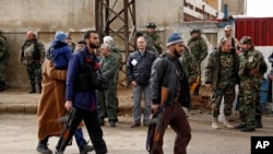 Des hommes armés et quelques familles quittent le quartier d’al-Waer pour la ville turque voisine, à Hams, Syrie, 18 mars 2017.