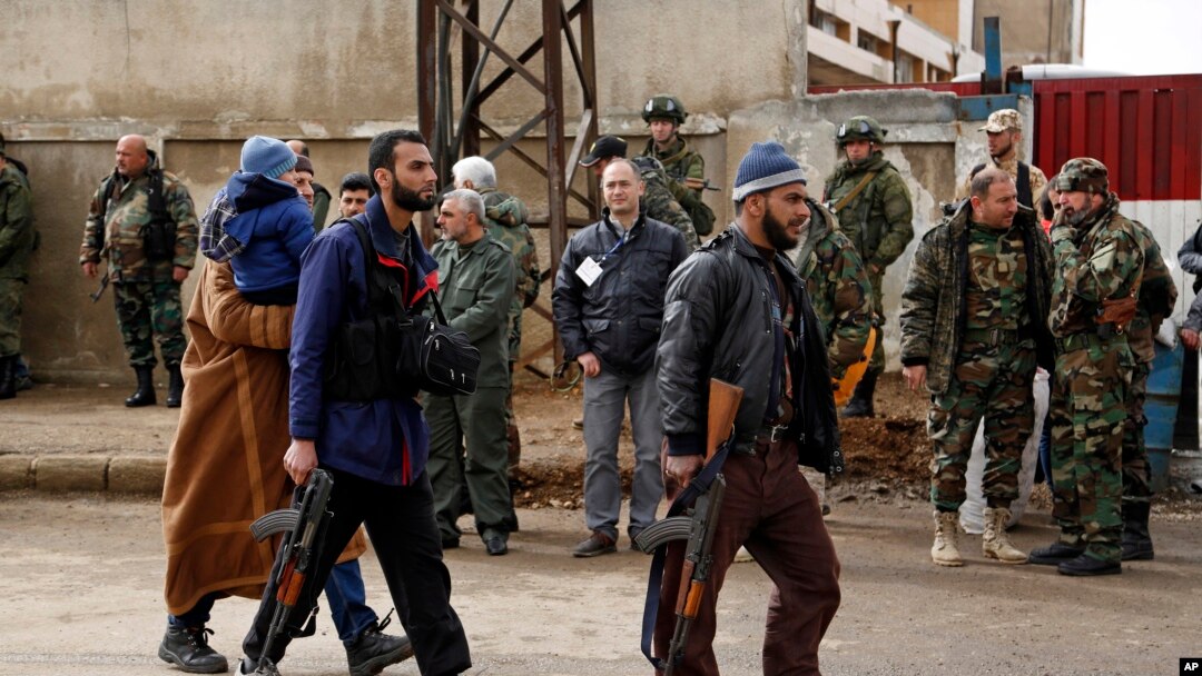 Gunmen carrying their weapons and some family members leave the al-Waer neighborhood bound for a town on the Turkish border, in Homs, Syria, Saturday, March 18, 2017. 