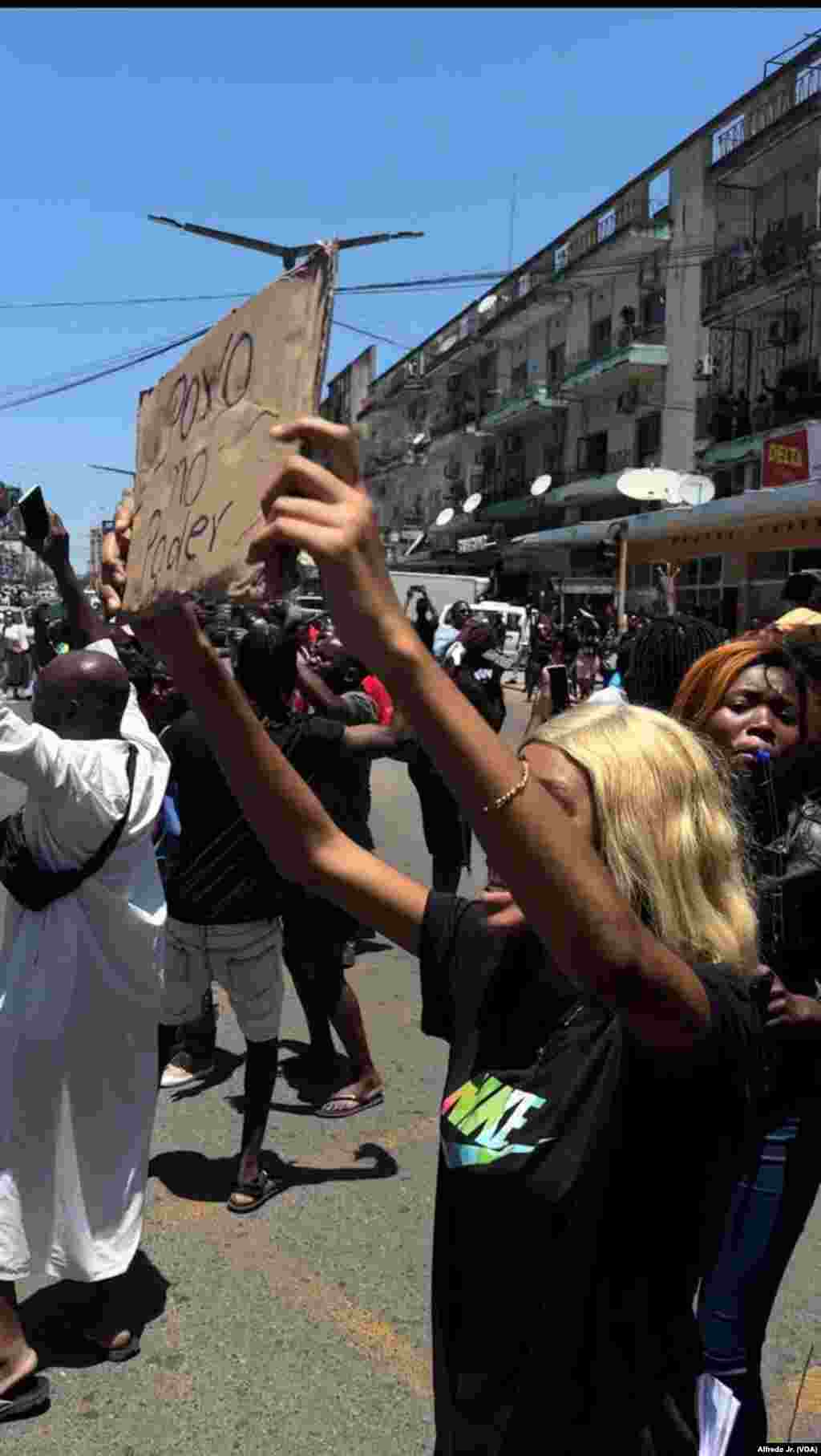 Segurando um cartaz com os dizeres “Povo no Poder”, uma cidadão participa no protesto dos buzinões em Maputo, Moçambique. 21 novembro 2024