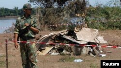 Seorang tentara Laos menjaga lokasi kecelakaan pesawat di dekat Sungai Mekong (19/10). 