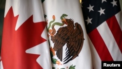 FILE - From left, the flags of Canada, Mexico and the United States are pictured at NAFTA talks in Mexico City, Nov. 19, 2017. 