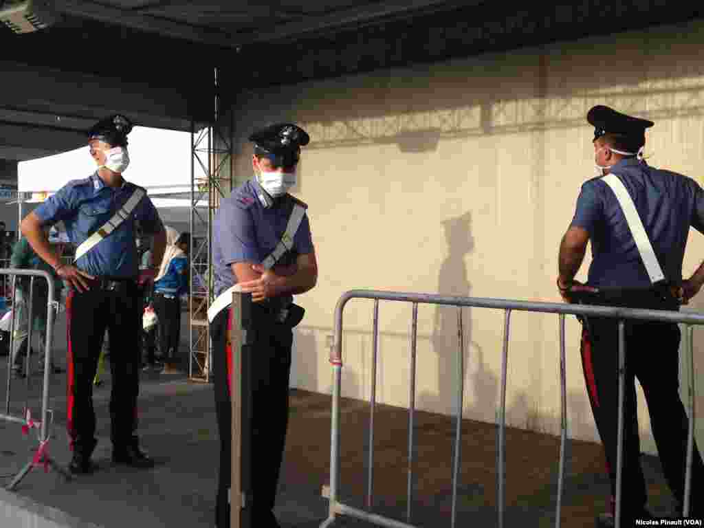 Italian policemen wearing masks as they are processing migrants in Catania.