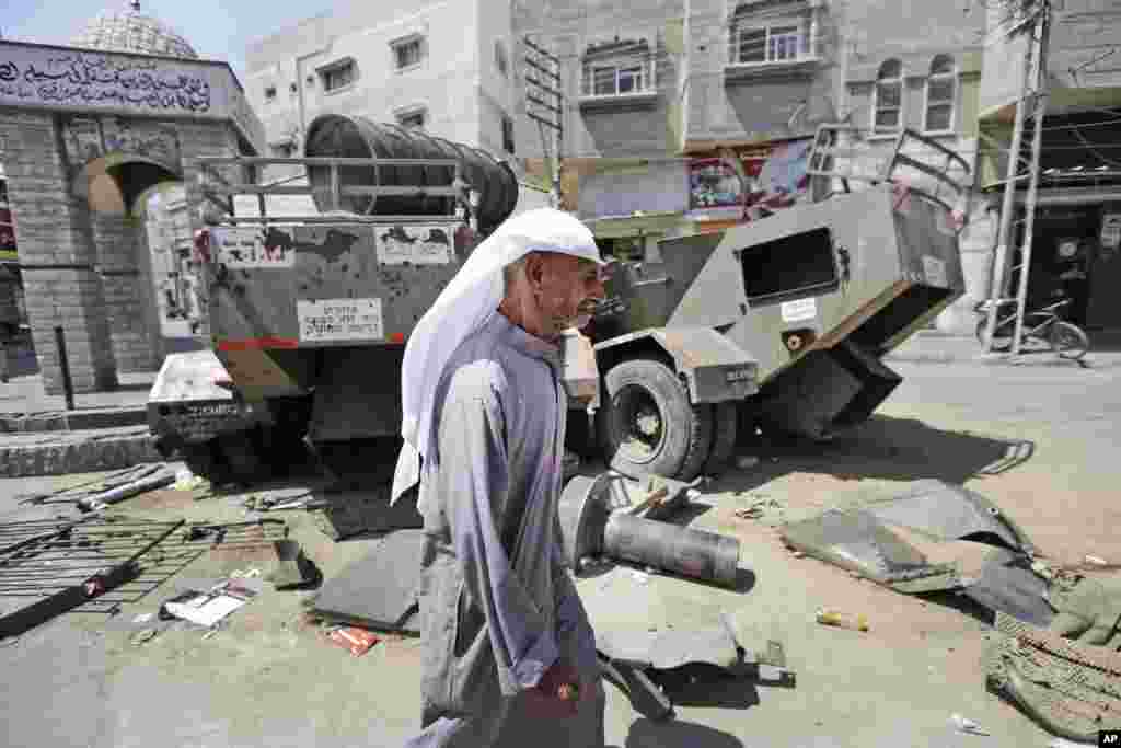 A man walks by parts of Israeli military vehicles left behind during the ground operation in Khan Younis, southern Gaza Strip, Monday, Aug. 11, 2014.