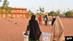 Election workers arrive with ballot boxes at the polling station during Niger's presidential election run off, in Niamey on February 21, 2021. (Photo by Issouf SANOGO / AFP)