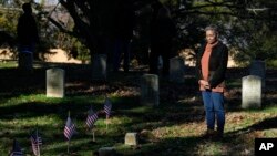 FILE —Thelma Sims Dukes observes small American flags by grave markers of Civil War soldiers of the United States 1st Mississippi Infantry (African Descent) in Vicksburg National Cemetery, February 14, 2024, in Vicksburg, Mississippi. 