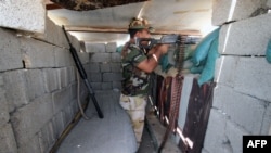 FILE - A member of the allied Iraqi forces, which consists of the Iraqi army and fighters from the Popular Mobilization units, guards a lookout point during clashes with Islamic State fighters on the outskirts of Fallujah, in Iraq's Anbar province, Aug. 13, 2015