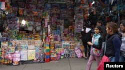 FILE - People walk past a stand that sells toys and other products imported from China at Central Market in Lima, Peru, Aug. 9, 2018. 